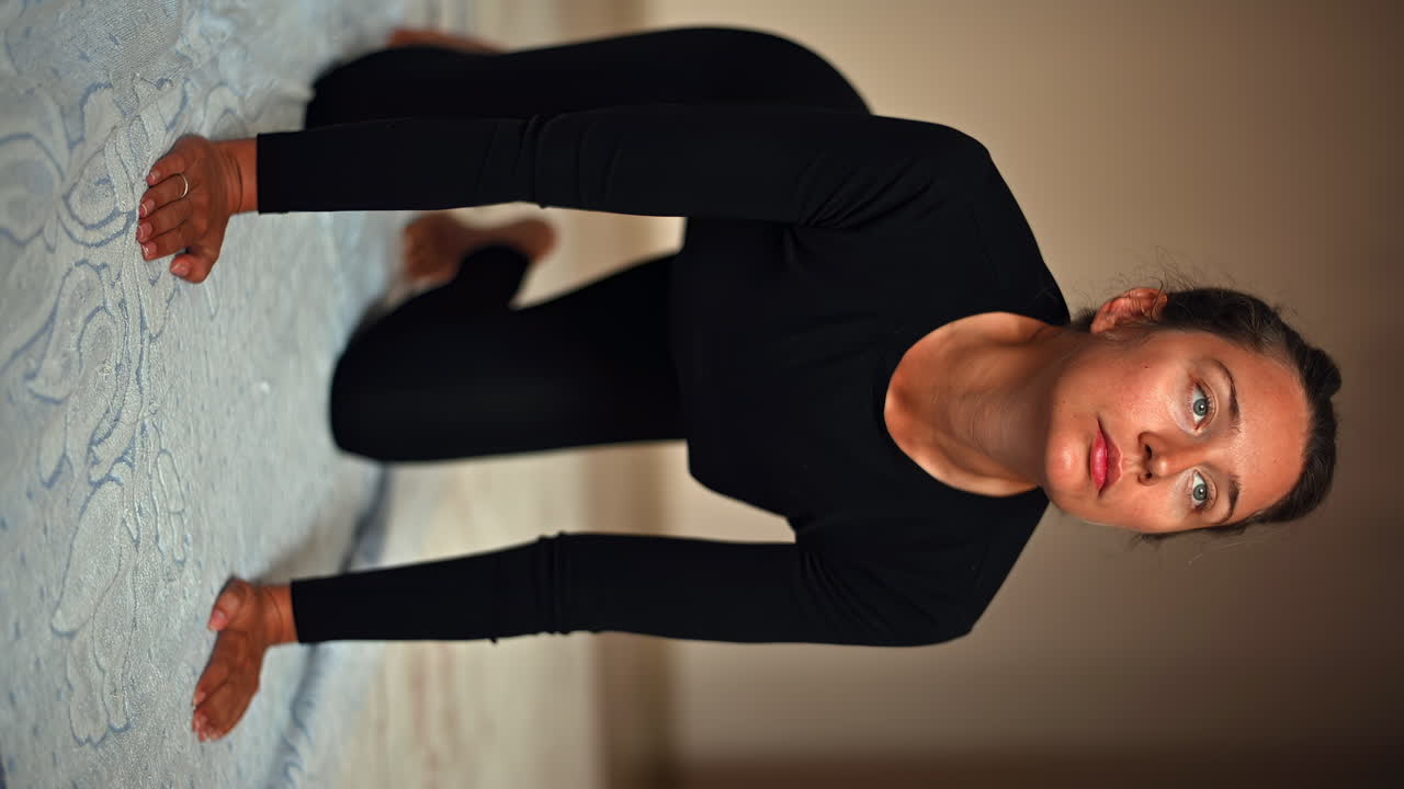 A woman engages in yoga on a soft mat in a calm indoor space. The warm morning light enhances the peaceful atmosphere as she focuses on her breath and movement
