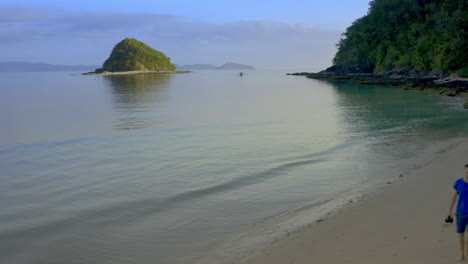 couple walking along a tropical beach with islands