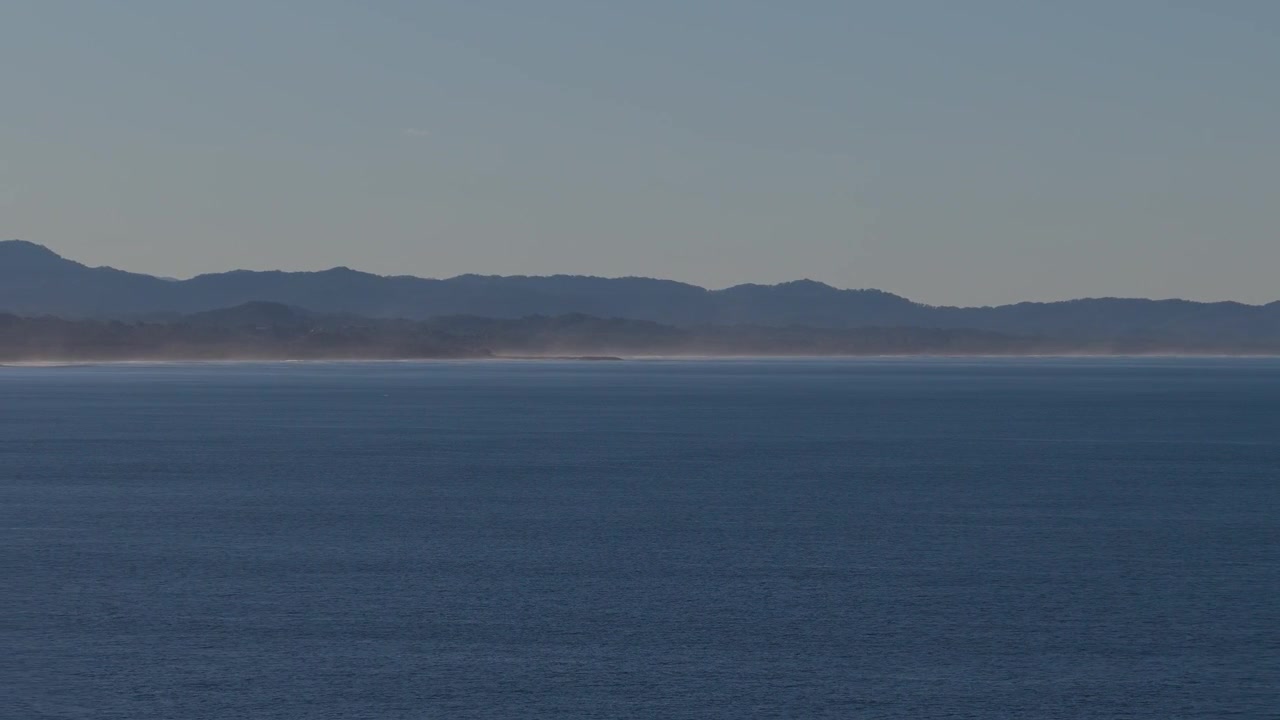 Kamerakjøring som beveger seg fra høyre til venstre over havet mot kystlinjen ved Belongil Beach og Julian Rocks nær Byron Bay, New South Wales, Australia.