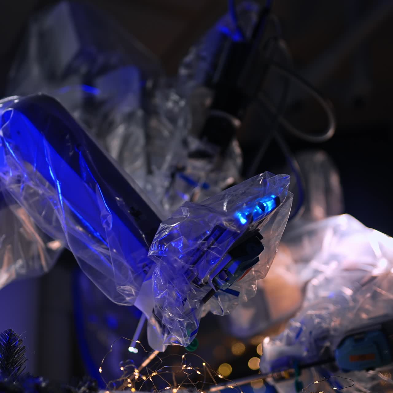 Futuristic robotic arms covered with plastic moving in the dark surgery room. Christmas decorations on the operational table