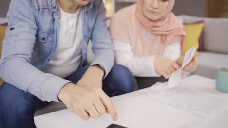 Muslim-couple-discussing-financial-debt-issue-checking-bills-at-home.