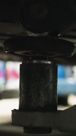 primer plano de un ascensor de automóvil posicionado debajo del vehículo en un taller de reparación de automóviles, centrándose en detalles mecánicos con movimientos sutiles en un fondo borroso