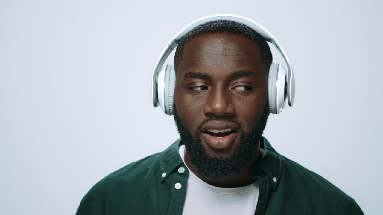 Ritratto di ragazzo africano gioioso che ascolta musica in cuffia in studio