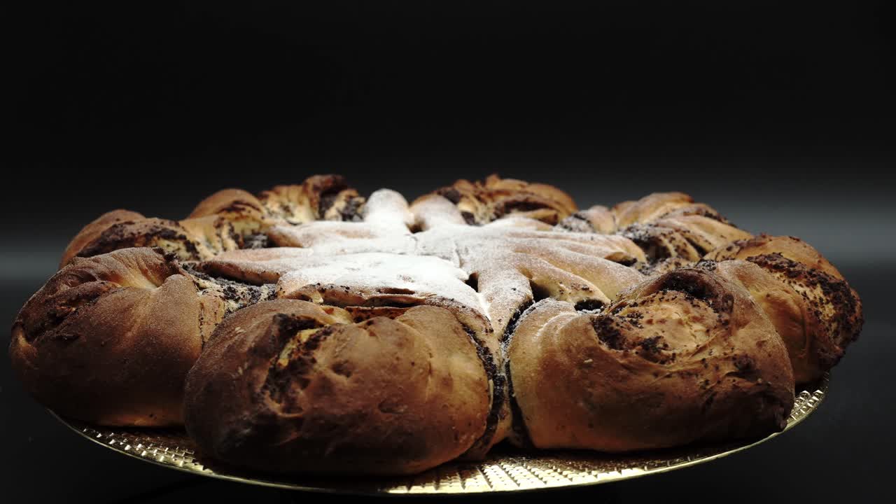 exhibiendo pastel festivo en forma de estrella: rollo tradicional de semillas de amapola polaco, makowiec sobre fondo negro