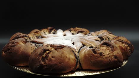 exhibiendo pastel festivo en forma de estrella: rollo tradicional de semillas de amapola polaco, makowiec sobre fondo negro
