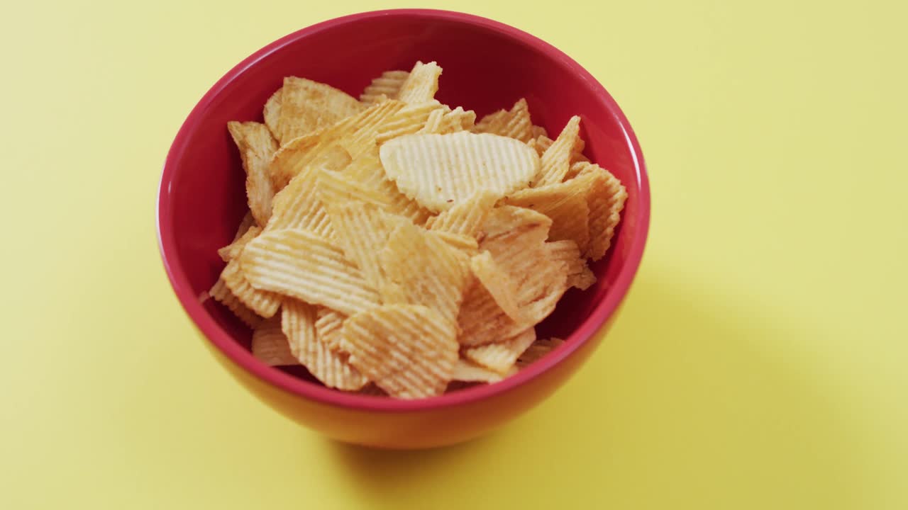 Primo piano di patatine fritte in una ciotola con spazio per il testo su superficie gialla.
