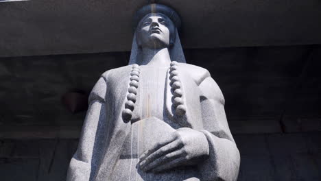 una rudimental estatua de piedra tallada de una figura femenina al estilo tradicional balcánico que sostiene el pórtico de piedra del mausoleo de njegos en la cima del monte lovcen en montenegro, inclinación lenta, toma de 4k