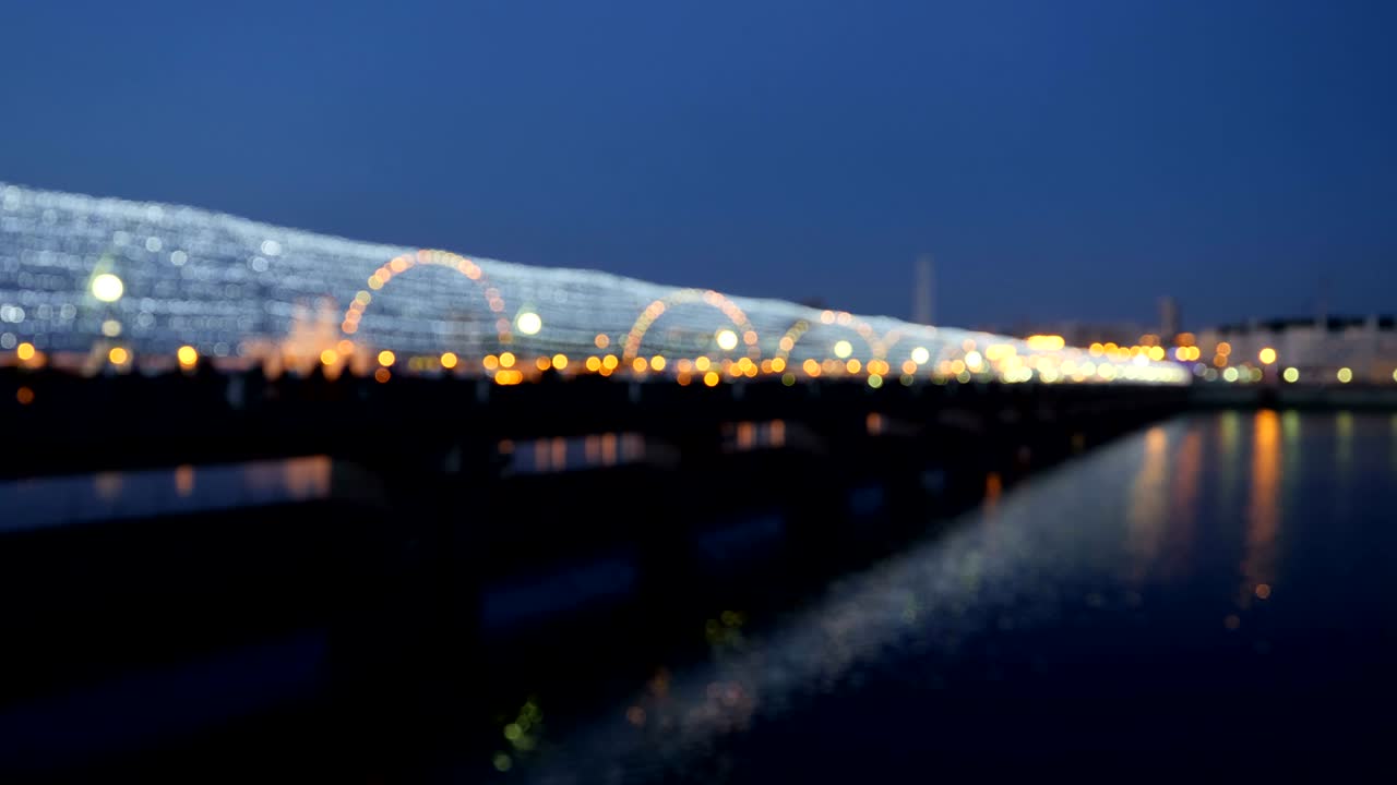 다리의 어두운 배경은 밤에 다리의 사람들로 가득 차 있습니다.