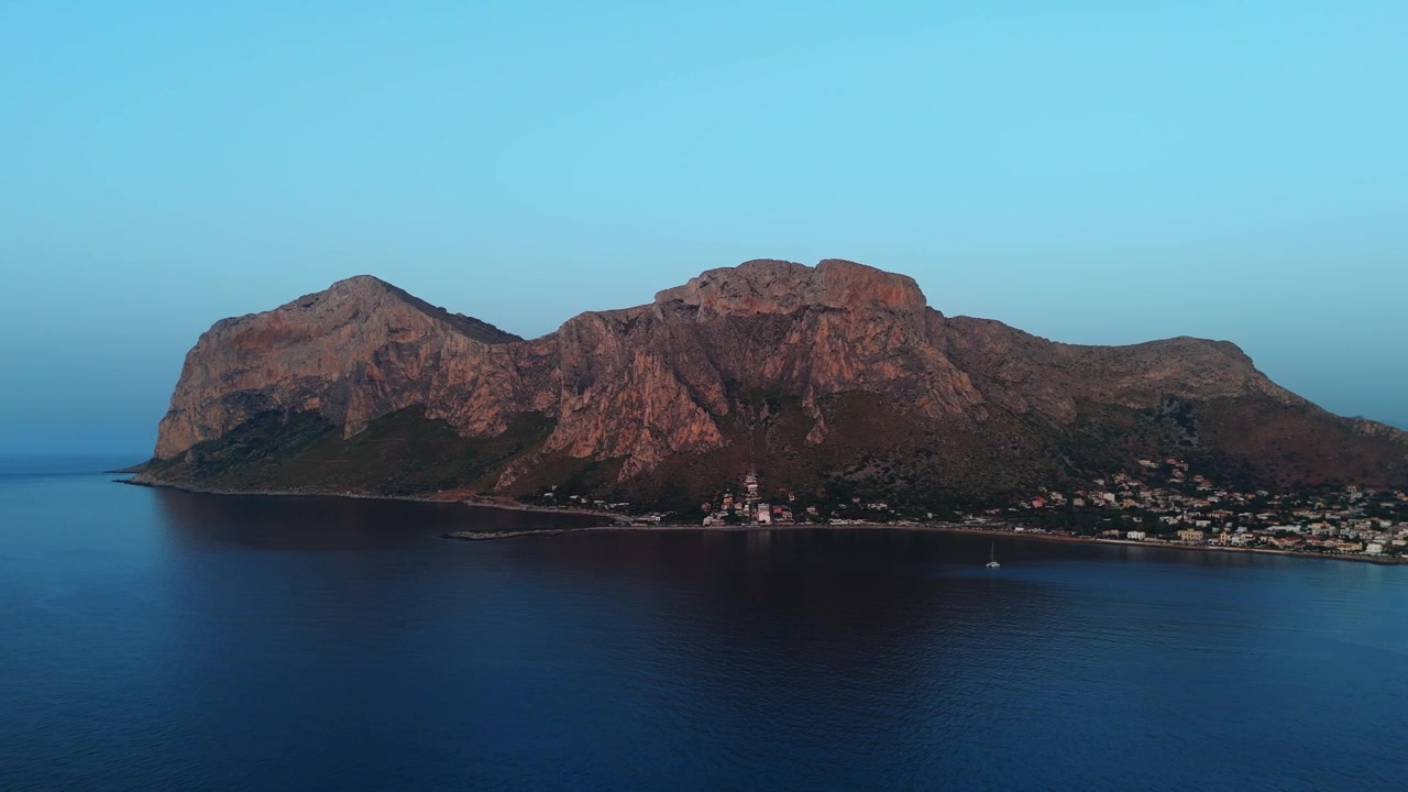 Vue de drone au coucher du soleil du promontoire de Capo Gallo et de la baie de Sferracavallo à Palerme, capturant la silhouette côtière au crépuscule.