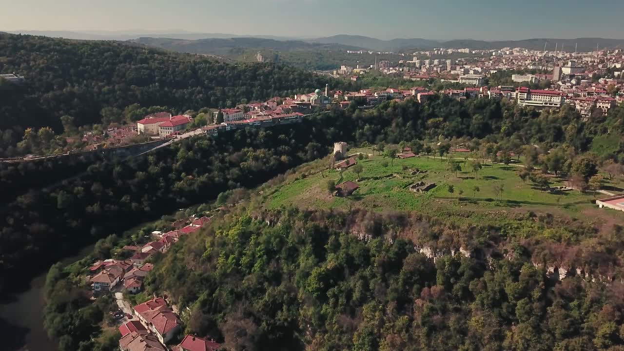 drone inclinado para a frente disparado sobre uma colina com um sítio arqueológico em veliko tarnovo