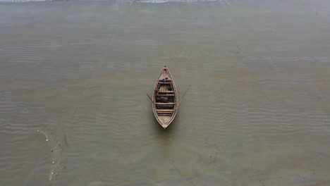 zoomed-out shot of a lone wooden boat on the tranquil beach in bangladesh