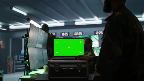 soldado usando software de seguimiento en la computadora portátil de pantalla verde para obtener información contra los enemigos