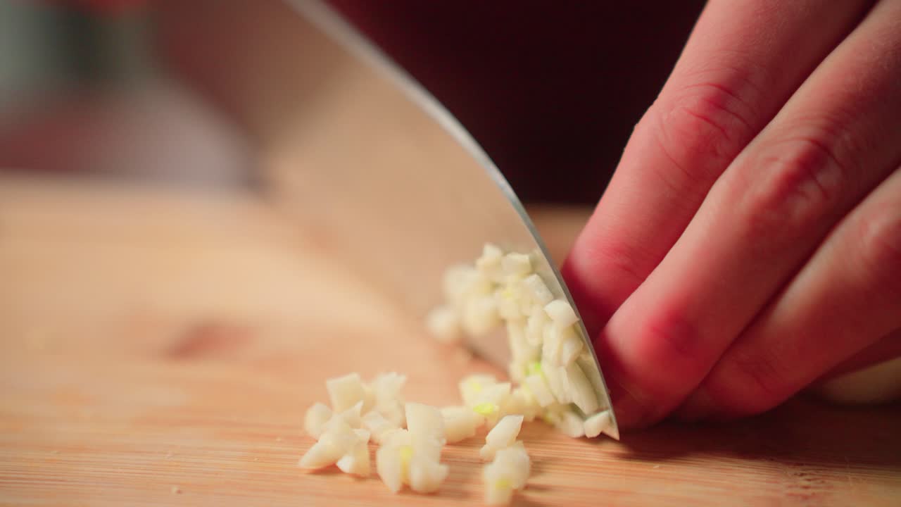 женщина режет зубчики чеснока рукой с ножом на режущей доске