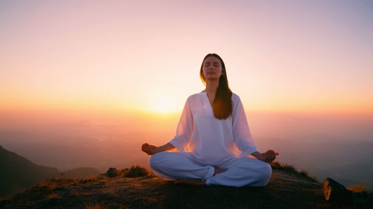 Mujer caucásica meditando pacíficamente en la cima de una montaña al amanecer, con luz dorada suave, ropa blanca fluida.