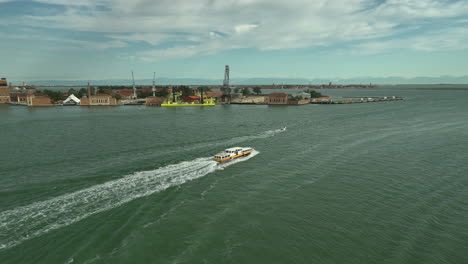 Venice-ferry-boat-cruising-in-front-of-Basilica-san-Pietro-di-Castello-on-the-way-to-Murano,-drone-truck-pan-4k