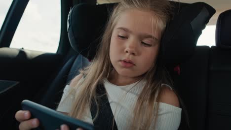 Niña-Caucásica-De-6-Años-Usando-Un-Teléfono-Móvil-Mientras-Viaja-En-Coche.