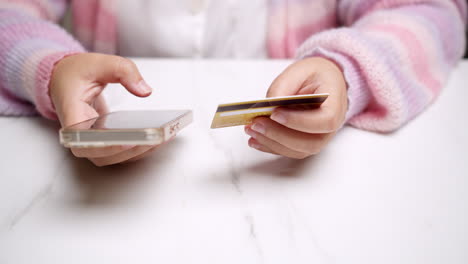 close-up woman's hand holds a smartphone and use a mockup bank credit card for online shopping services to pay money with cashless technology