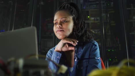 african american female computer technician using laptop working in business server room