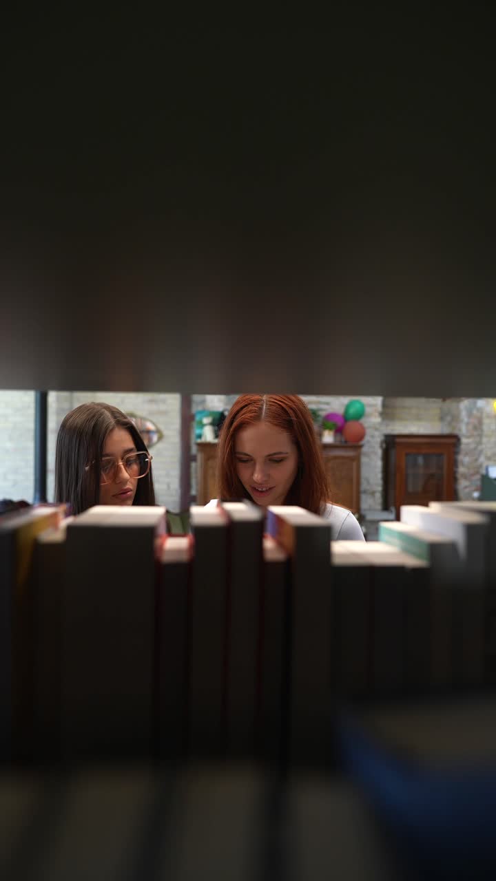 Due giovani donne che sfogliano libri in una biblioteca