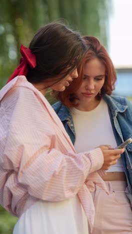 two young women looking at a phone outdoors