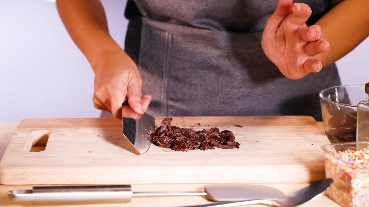Person chopping chocolate discs with a knife