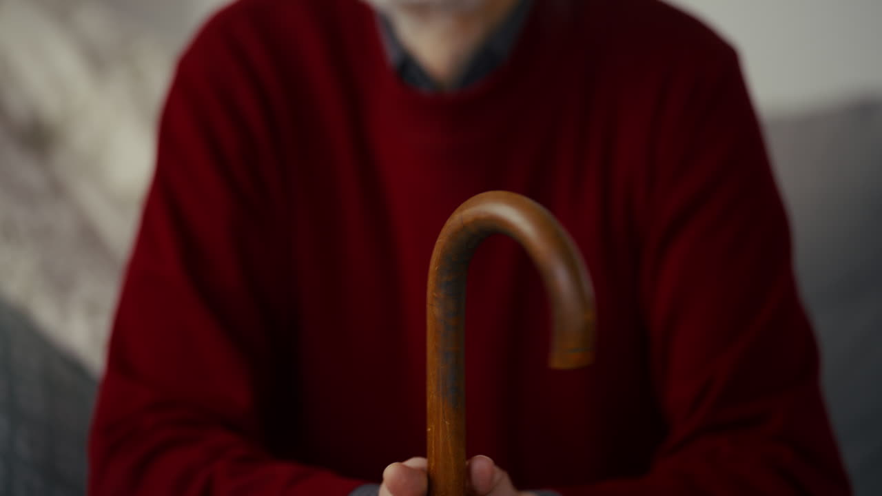 Primo piano di uomo anziano che tiene un bastone da passeggio e appare pensieroso