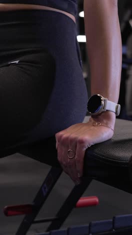 vertical shot of a woman resting on a bench whilst recvovering for her next set