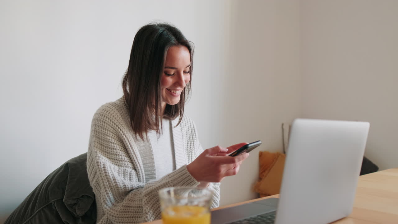 Mulher usando laptop e smartphone em casa