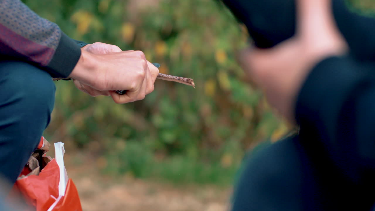 마시멜로를 굽는 데 사용할 수 있도록 막대기를 갈고 있습니다.