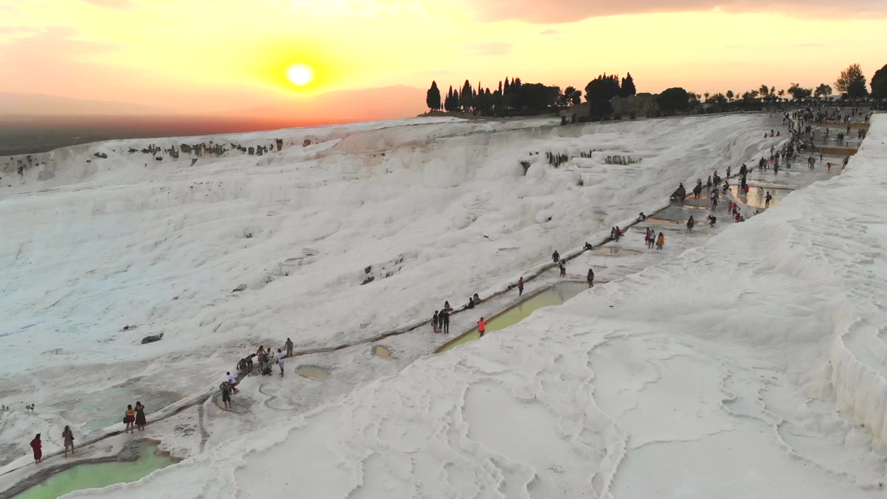 Tourists Walking on White Travertine Terraces at Pamukkale During Sunset