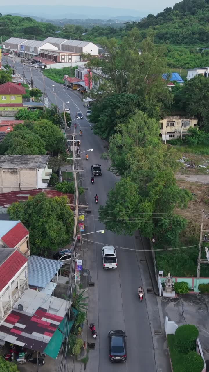 Aerial view of a city street with cars, motorcycles, and buildings