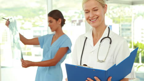 doctor looking at camera with her colleagues behind