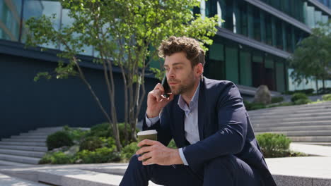 businessman discussing work cellphone call sitting street stairs with coffee cup