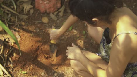 the hand of an elderly woman in a glove digs a hole in the ground with a shovel for planting a plant