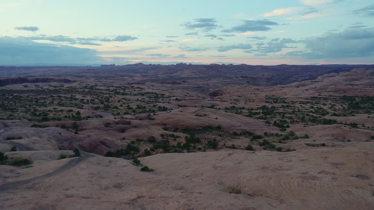 un drone de seguimiento de 4k de un jeep levantado fuera de carretera a través del paisaje desértico extremo y rocoso cerca de moab, utah, con las montañas rocosas nevadas que se elevan en la distancia