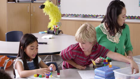 Teacher-sits-with-young-kids-in-school-class,-shot-on-R3D