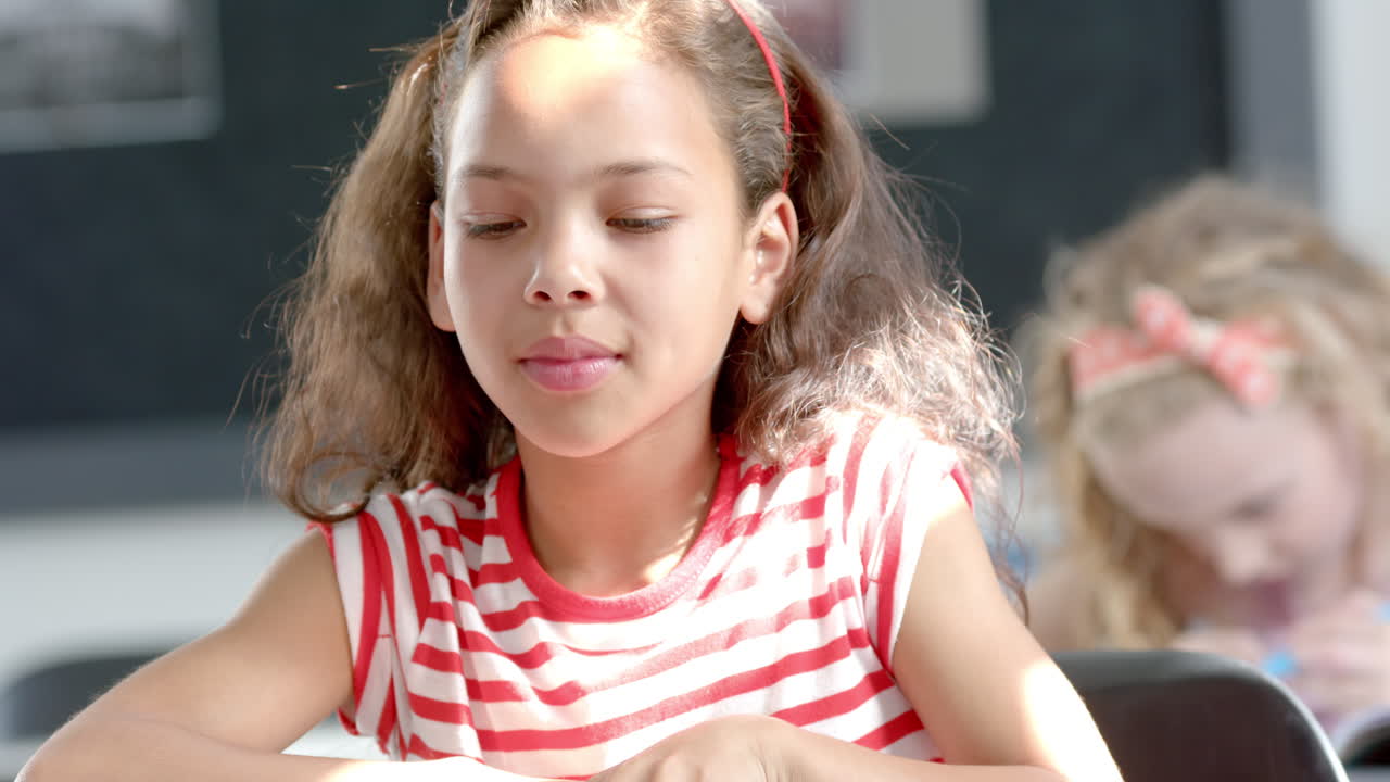 In school, girl in striped shirt closing eyes and relaxing in classroom