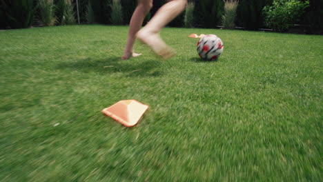 child practicing soccer dribbling in a garden