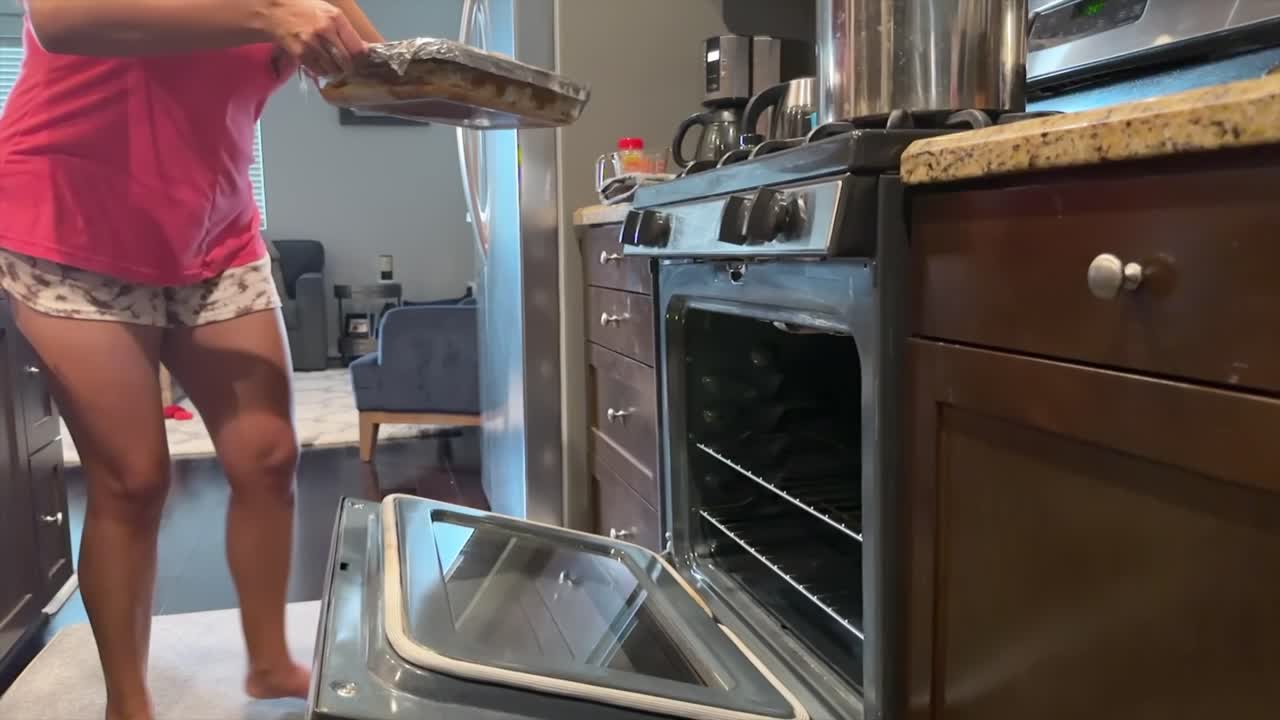 Hispanische Frau schiebt Lasagneform in Zeitlupe in den Ofen, hausgemachtes Gericht.
