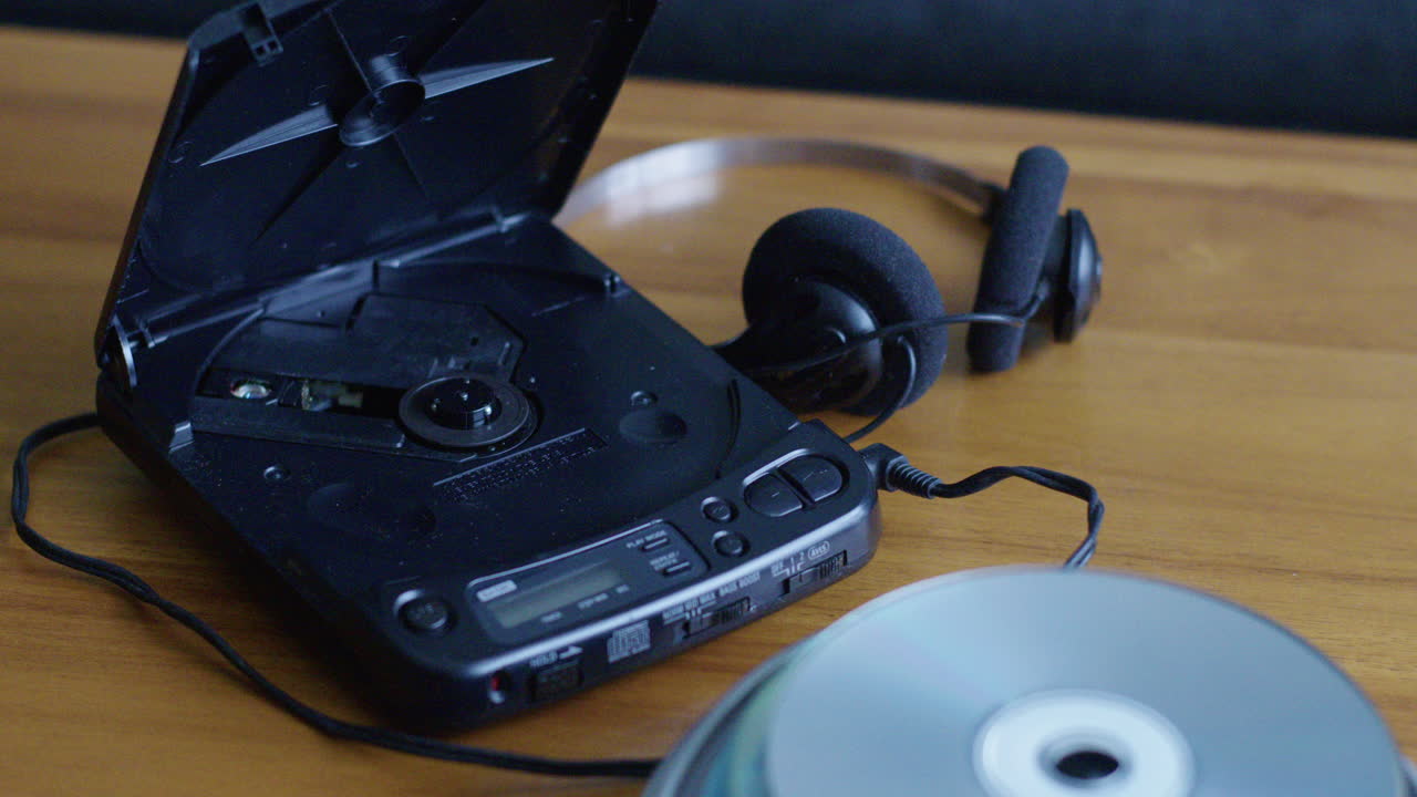 Close Up Tilt Up of a CD Player and Compact Discs on a Table