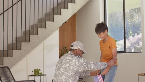 military indian father in uniform greeting young son holding american flag at home