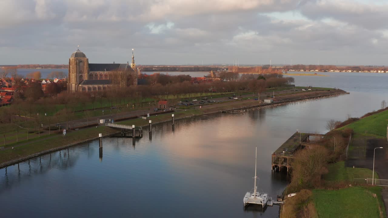 The entrance to a canal with in the background a historical city and manmade lake. Drone shot
