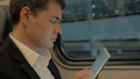 young businessman chatting on pad in the train