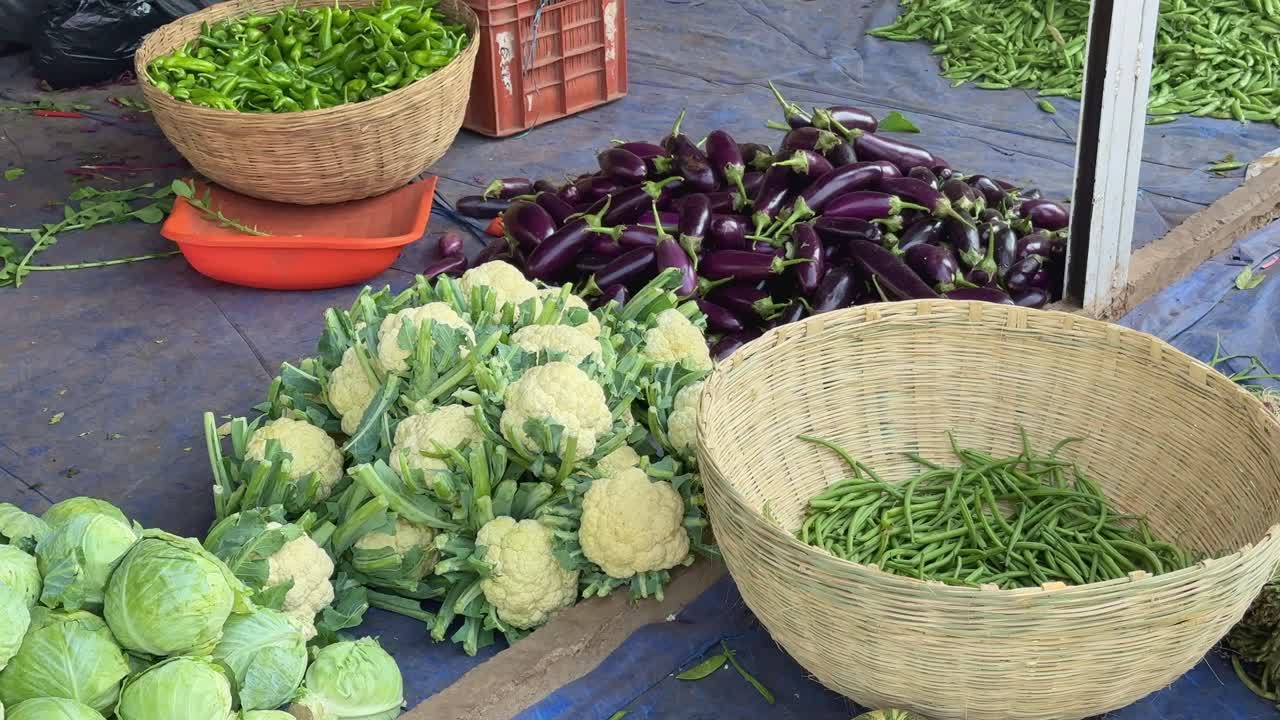 a pile of cabage and cauliflower and eggplant at the market for sale