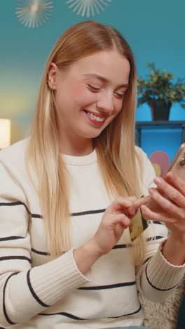 caucasian woman paying purchase on sofa with mobile phone credit card smiling successful indoors