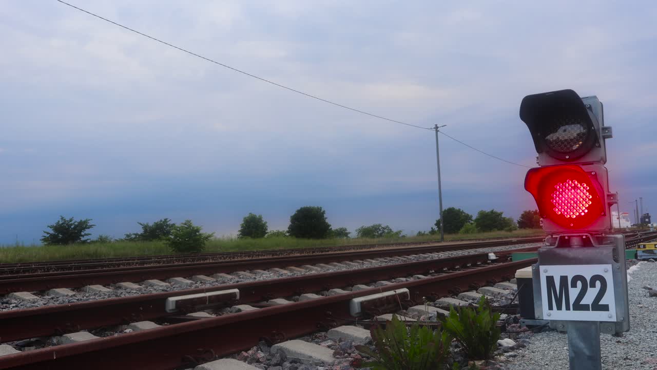 빨간색 열차 신호등과 열차 트랙의 영상과 구름이 많은 파란 하늘이 배경에 보입니다.