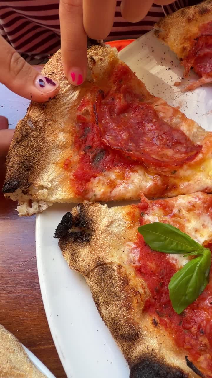 Primo piano di mani che separano e mangiano una deliziosa pizza al salame piccante