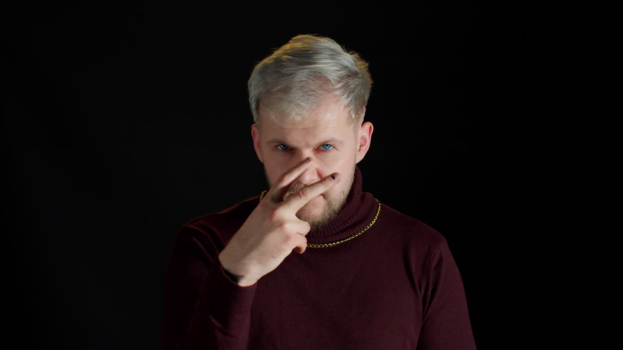 joven seductor con ropa elegante de moda sosteniendo las manos cerca de los ojos fingiendo mirarte