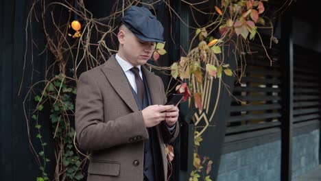 young stylish businessman using smartphone on street. a man texting messages, cheating on his smartphone near the office center. business. social networking