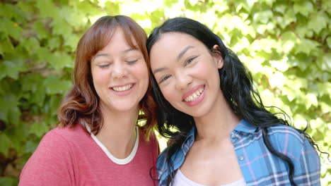 two young biracial female friends are smiling with their heads close together